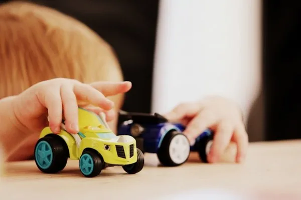 Niño pequeño jugando con carritos de juguete