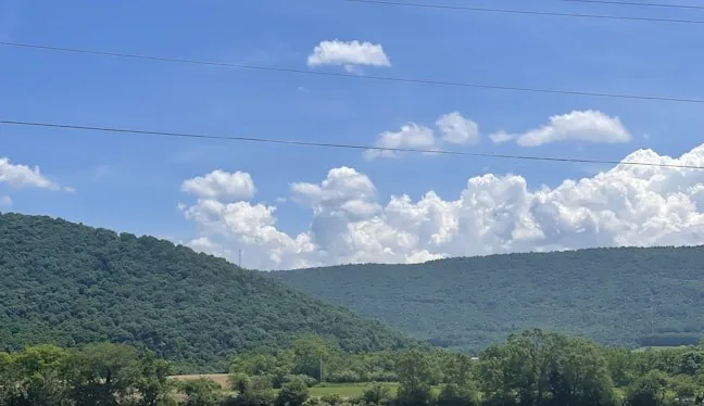 Paved rail trail through green rolling hills