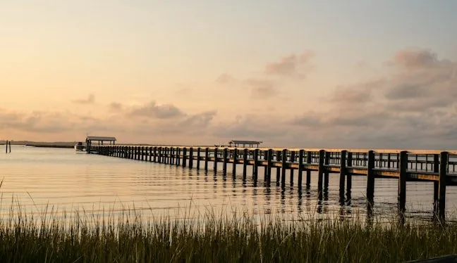 Fishing pier over calm bay water at dusk